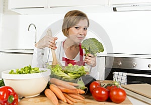 Young beautiful home cook woman at modern kitchen preparing vegetable salad bowl smiling happy