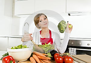 Young beautiful home cook woman at modern kitchen preparing vegetable salad bowl smiling happy