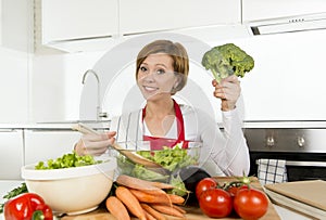 Young beautiful home cook woman at modern kitchen preparing vegetable salad bowl smiling happy