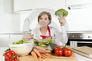 Young beautiful home cook woman at modern kitchen preparing vegetable salad bowl smiling happy