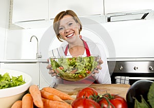 Young beautiful home cook woman at modern kitchen preparing vegetable salad bowl smiling happy