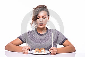 Young beautiful hungry woman holding sushi with chopsticks isolated on white background