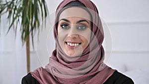 Young beautiful Indian girl in pink hijab smiling and looking at camera. Portrait, white background, close up 60 fps