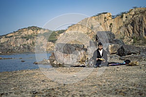 Young beautiful indian girl reading a book while leaning down on the ground wearing a black coat. Concept of having picnic in a