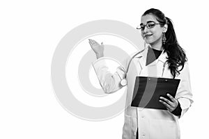 Young beautiful Indian woman doctor holding clipboard while showing something