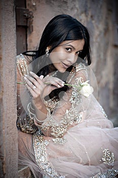 Young beautiful Indian Woman sitting against stone wall outdoors