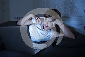 Young beautiful internet addicted sleepless and tired woman working on laptop in bed late at night