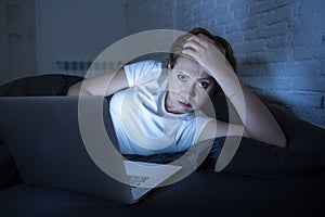 Young beautiful internet addicted sleepless and tired woman working on laptop in bed late at night