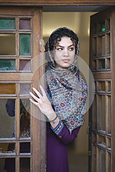 Young beautiful iranian lady looking out of a door