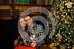 Young beautiful kisser and burning sparklers. Loving couple in Christmas decorated room.
