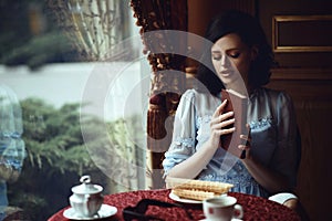 Young beautiful lady sitting at the table in the nice cozy cafÃ© with book in her hands.