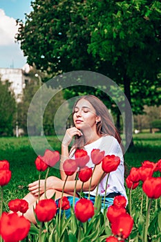 Young beautiful lady surrounded by tulips in spring