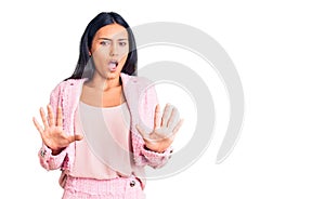 Young beautiful latin girl wearing business clothes afraid and terrified with fear expression stop gesture with hands, shouting in