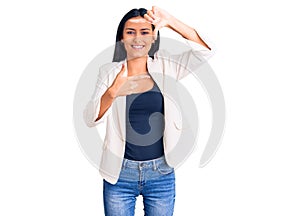Young beautiful latin girl wearing business clothes smiling making frame with hands and fingers with happy face