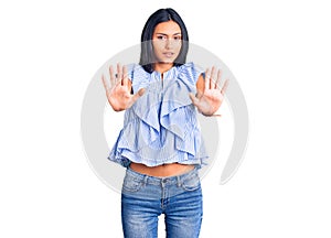 Young beautiful latin girl wearing casual clothes afraid and terrified with fear expression stop gesture with hands, shouting in