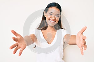 Young beautiful latin girl wearing casual white tshirt looking at the camera smiling with open arms for hug