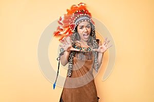 Young beautiful latin girl wearing indian costume afraid and terrified with fear expression stop gesture with hands, shouting in