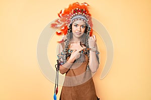 Young beautiful latin girl wearing indian costume in hurry pointing to watch time, impatience, looking at the camera with relaxed