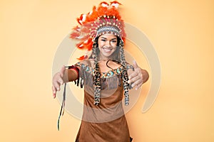 Young beautiful latin girl wearing indian costume looking at the camera smiling with open arms for hug