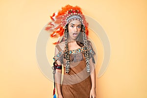 Young beautiful latin girl wearing indian costume in shock face, looking skeptical and sarcastic, surprised with open mouth