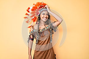Young beautiful latin girl wearing indian costume smiling confident touching hair with hand up gesture, posing attractive and
