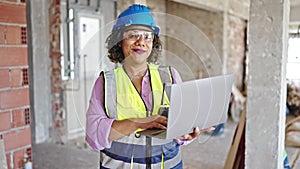 Young beautiful latin woman builder smiling confident using laptop at construction site