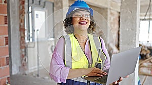 Young beautiful latin woman builder smiling confident using laptop at construction site