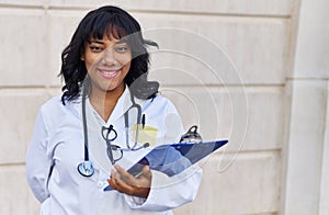 Young beautiful latin woman doctor smiling confident holding clipboard at hospital
