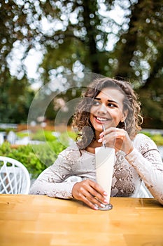 Young beautiful latin woman sitting in a cafe drinking a milkshake