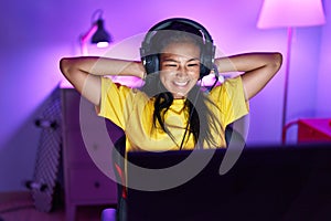 Young beautiful latin woman streamer smiling confident relaxed with hands on head at gaming room