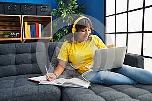 Young beautiful latin woman student writing on notebook studying at home