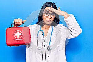 Young beautiful latin woman wearing doctor stethoscope holding first aid kit stressed and frustrated with hand on head, surprised