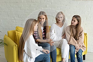 Young beautiful lesbian family in casual clothes sitting on yellow sofa at home