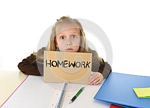 Young beautiful little schoolgirl sad and overwhelmed holding paper with the text homework