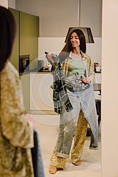 Young beautiful long haired smiling woman trying on clothes