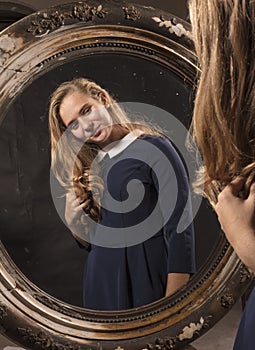 Young beautiful longhaired woman looking at vintage mirror