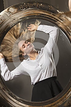 Young beautiful longhaired woman looking at vintage mirror