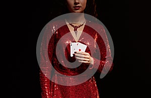 Young beautiful lucky brunette in a red evening dress shows her cards, a pair of aces