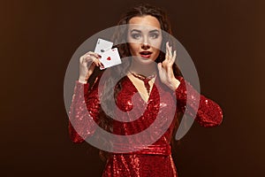 Young beautiful lucky brunette in a red evening dress shows her cards, a pair of aces