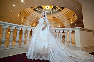 Young beautiful luxurious woman in wedding dress posing in luxurious interior. Bride with huge wedding dress in majestic manor