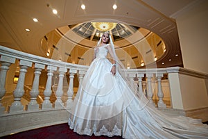 Young beautiful luxurious woman in wedding dress posing in luxurious interior. Bride with huge wedding dress in majestic manor