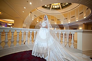 Young beautiful luxurious woman in wedding dress posing in luxurious interior. Bride with huge wedding dress in majestic manor