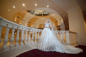 Young beautiful luxurious woman in wedding dress posing in luxurious interior. Bride with huge wedding dress in majestic manor