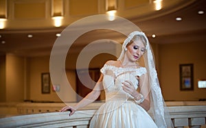 Young beautiful luxurious woman in wedding dress posing in luxurious interior. Bride with huge wedding dress in majestic manor