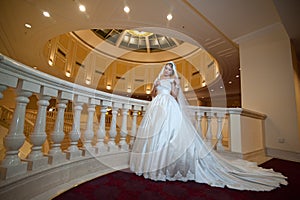 Young beautiful luxurious woman in wedding dress posing in luxurious interior. Bride with huge wedding dress in majestic manor
