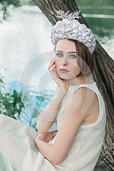 Young beautiful mermaid in seashells crown is sitting on the water background.Mermaid cosplay