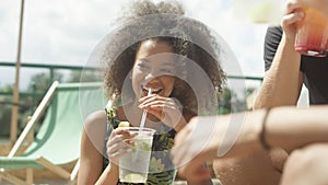 Young beautiful mixed race friends sitting on sunbeds under umbrella and enjoying vacation.