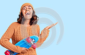 Young beautiful mixed race woman holding skate celebrating victory with happy smile and winner expression with raised hands