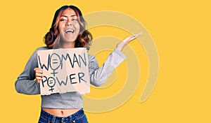 Young beautiful mixed race woman holding woman power banner celebrating victory with happy smile and winner expression with raised