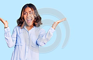 Young beautiful mixed race woman wearing casual business shirt celebrating victory with happy smile and winner expression with